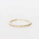 A dainty gold band with an intricate wave pattern all the way around.
