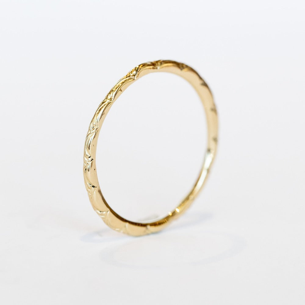 A dainty gold band with an intricate wave pattern all the way around.