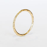 A dainty gold band with an intricate wave pattern all the way around.