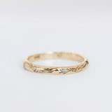 An engraved gold band with a domed contour and knotted rope engraving that encircles the band.