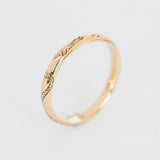 An engraved gold band with a domed contour and knotted rope engraving that encircles the band.