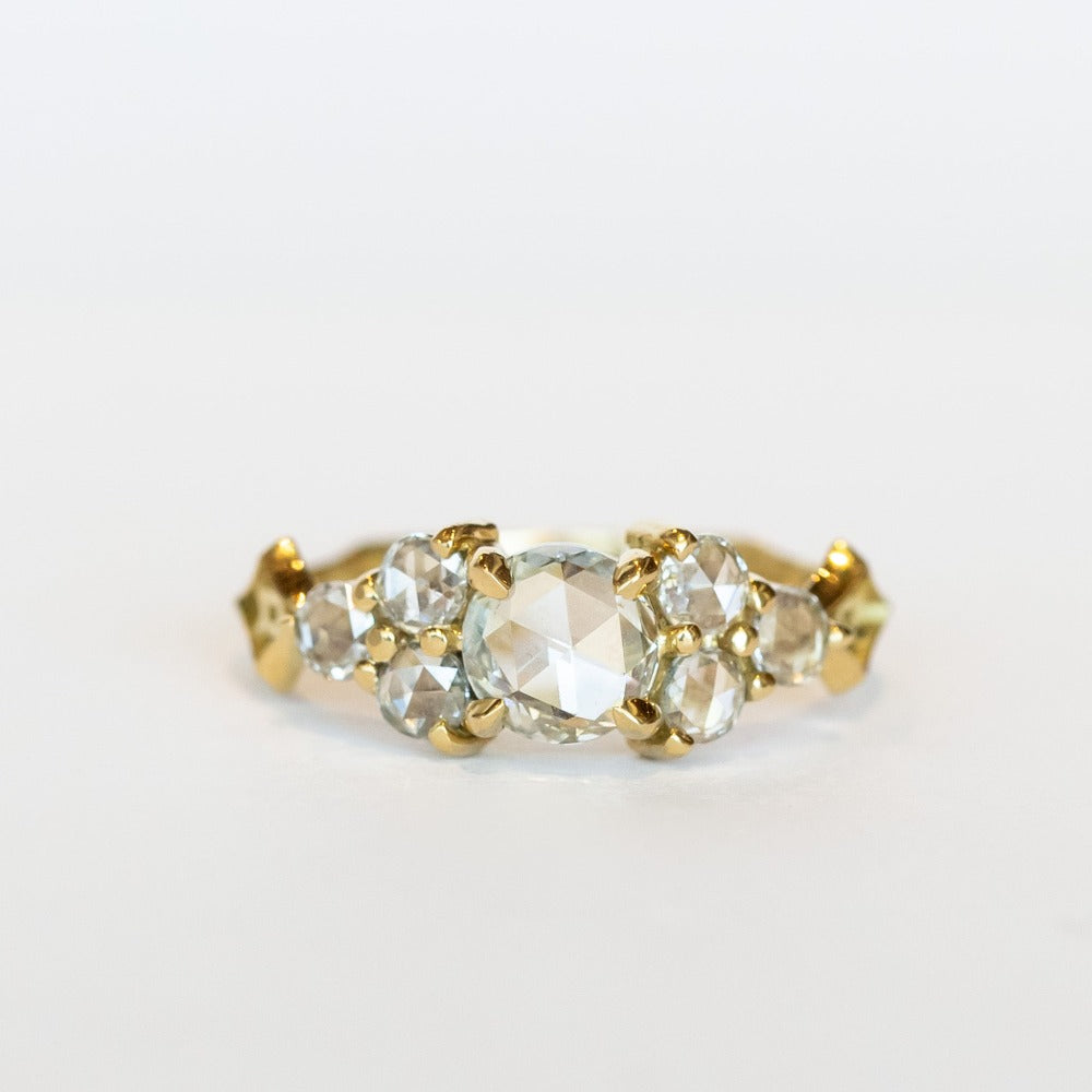 A diamond engagement ring that features a 1 carat rose cut center stone flanked by six rose cut side stones, in a polished 18k yellow gold setting.