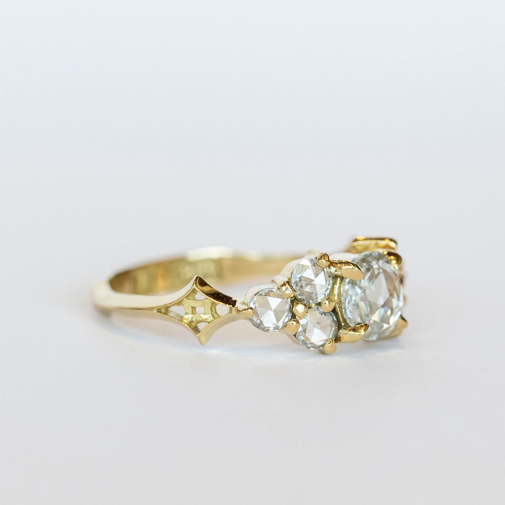 A diamond engagement ring that features a 1 carat rose cut center stone flanked by six rose cut side stones, in a polished 18k yellow gold setting.