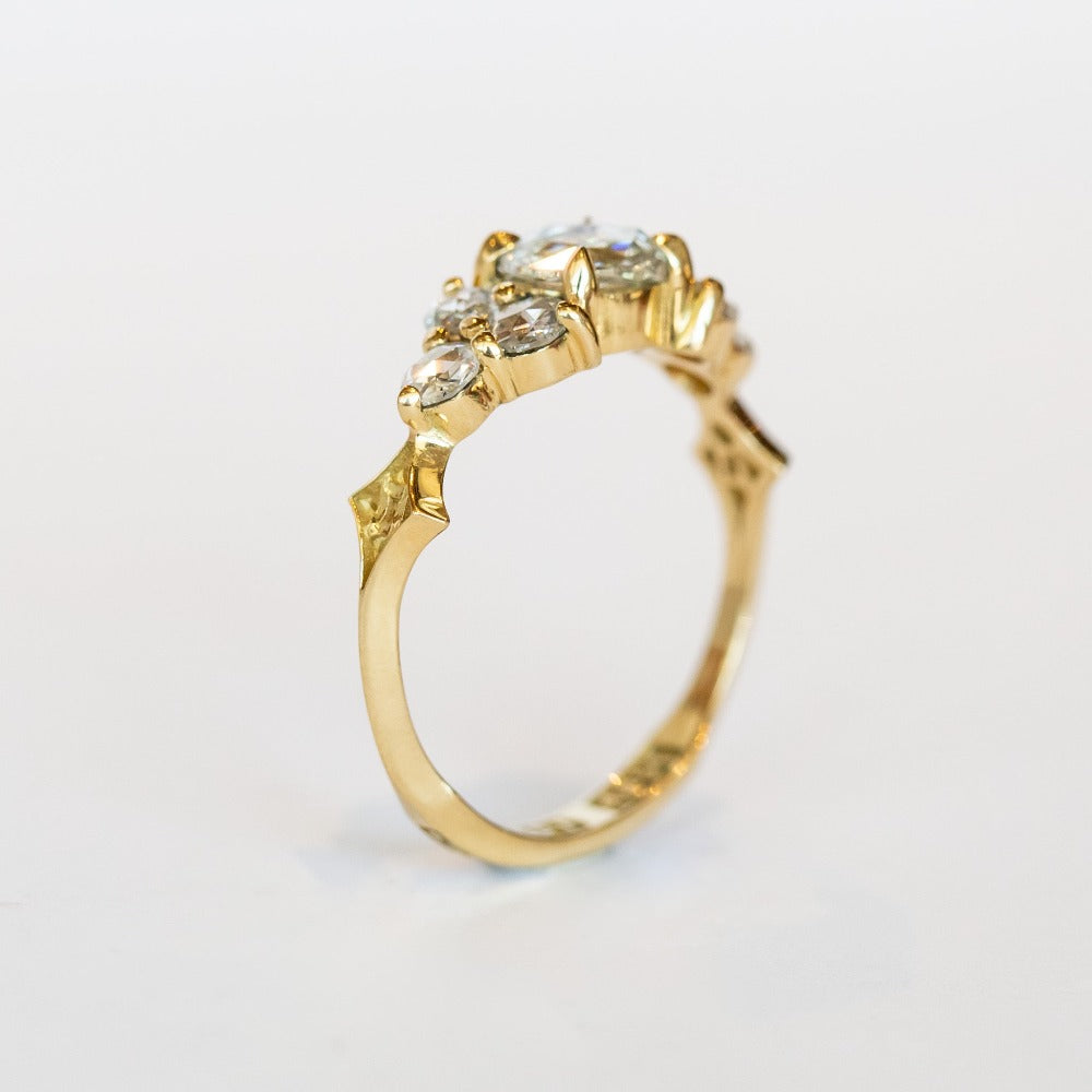 A diamond engagement ring that features a 1 carat rose cut center stone flanked by six rose cut side stones, in a polished 18k yellow gold setting.