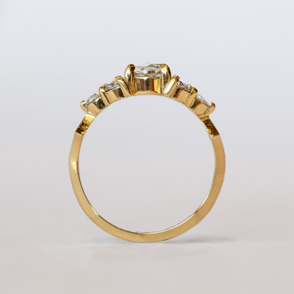 A diamond engagement ring that features a 1 carat rose cut center stone flanked by six rose cut side stones, in a polished 18k yellow gold setting.
