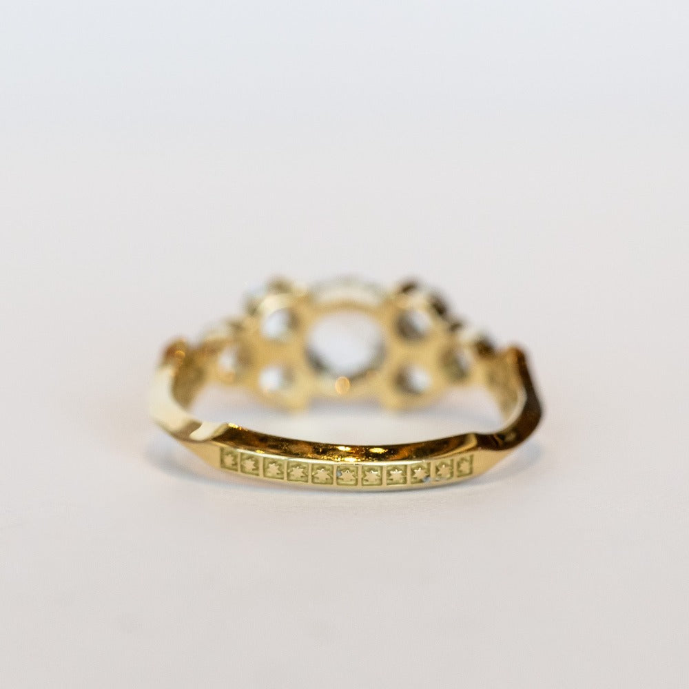 A diamond engagement ring that features a 1 carat rose cut center stone flanked by six rose cut side stones, in a polished 18k yellow gold setting.