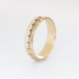A 5mm half-dome gold band with a wave pattern engraving along one edge that wraps around the entire band.