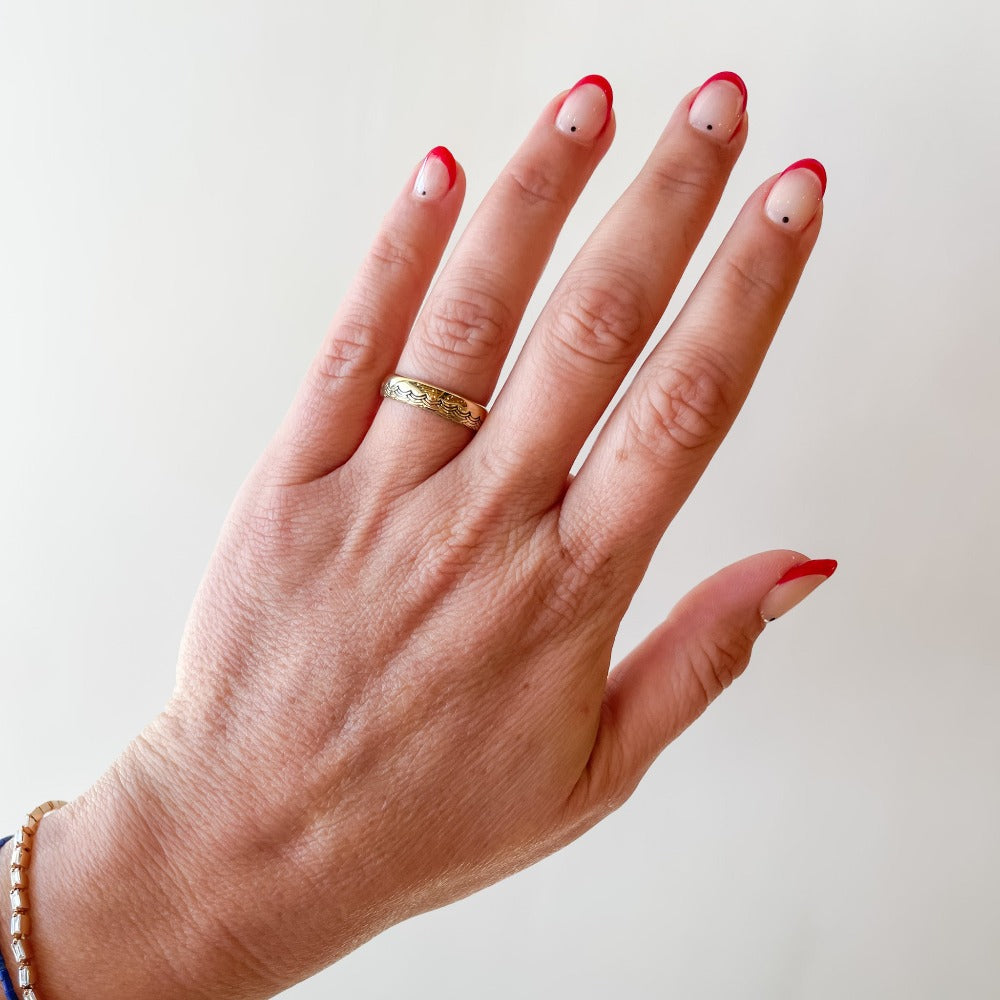 A 5mm half-dome gold band with a wave pattern engraving along one edge that wraps around the entire band.