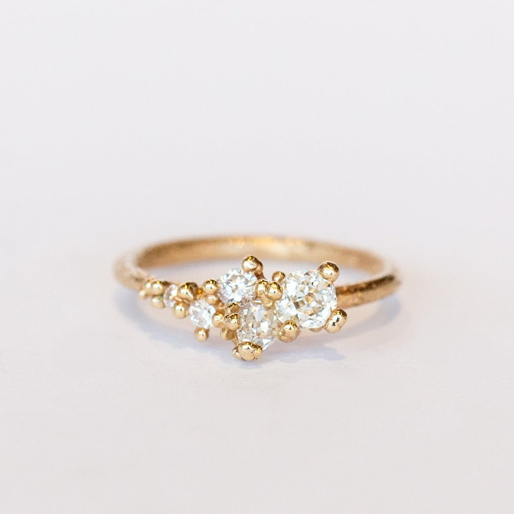 A tapering cluster of antique cut white diamonds all nestled amongst polished granules of rich yellow gold on a textured band.