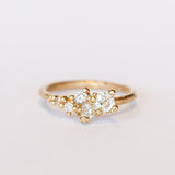 A tapering cluster of antique cut white diamonds all nestled amongst polished granules of rich yellow gold on a textured band.