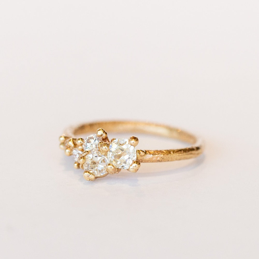 A tapering cluster of antique cut white diamonds all nestled amongst polished granules of rich yellow gold on a textured band.