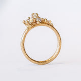 A tapering cluster of antique cut white diamonds all nestled amongst polished granules of rich yellow gold on a textured band.