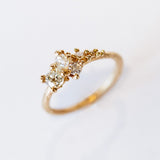 A tapering cluster of antique cut white diamonds all nestled amongst polished granules of rich yellow gold on a textured band.