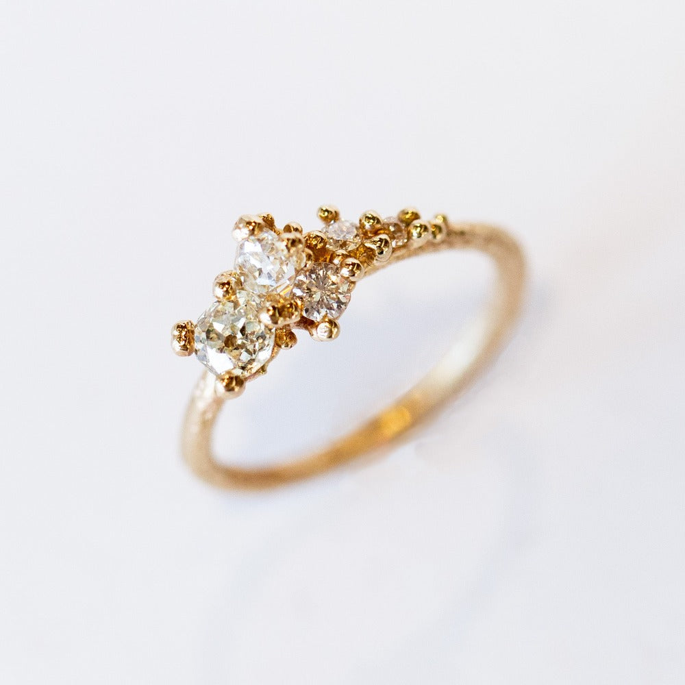 A tapering cluster of antique cut white diamonds all nestled amongst polished granules of rich yellow gold on a textured band.