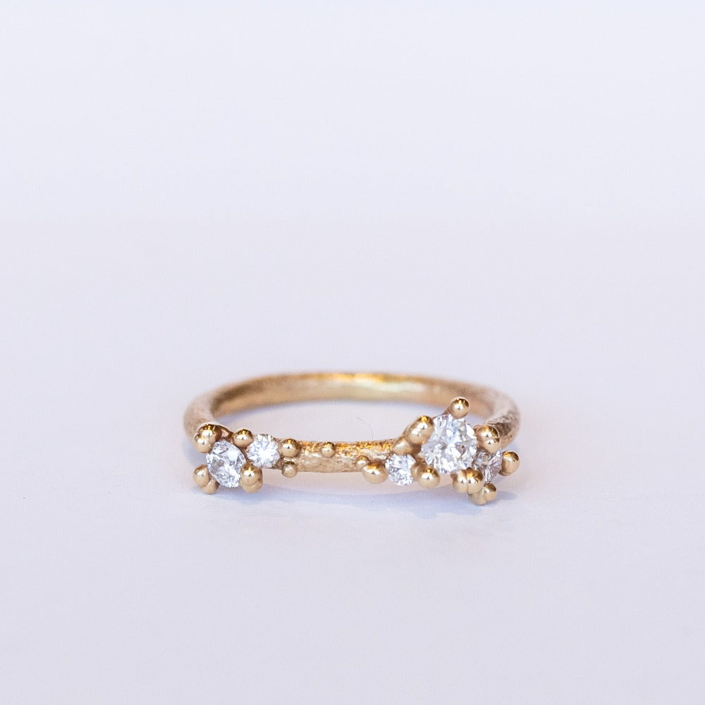 A textured gold band set with asymmetric clusters of small diamonds.
