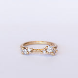 A textured gold band set with asymmetric clusters of small diamonds.