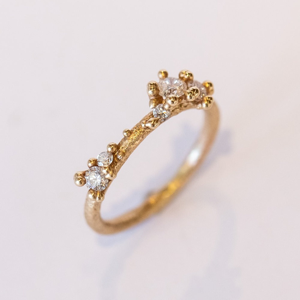 A textured gold band set with asymmetric clusters of small diamonds.