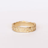A wide gold wedding band with intricate zig zag and dot detailing.