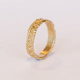 A wide gold wedding band with intricate zig zag and dot detailing.