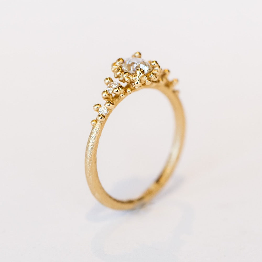 Unique antique cut diamond engagement ring with golden granules, on a gently textured band.