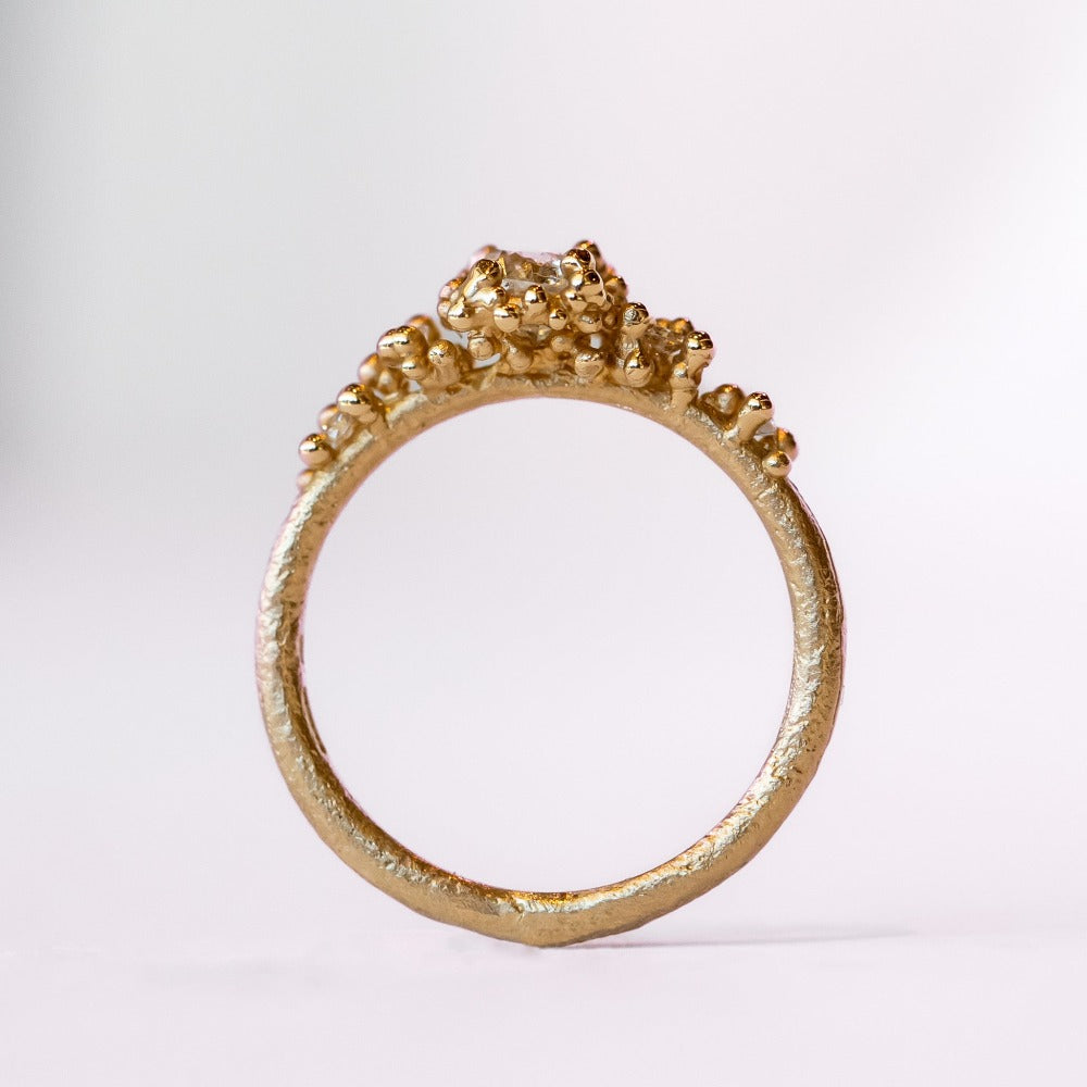 Unique antique cut diamond engagement ring with golden granules, on a gently textured band.