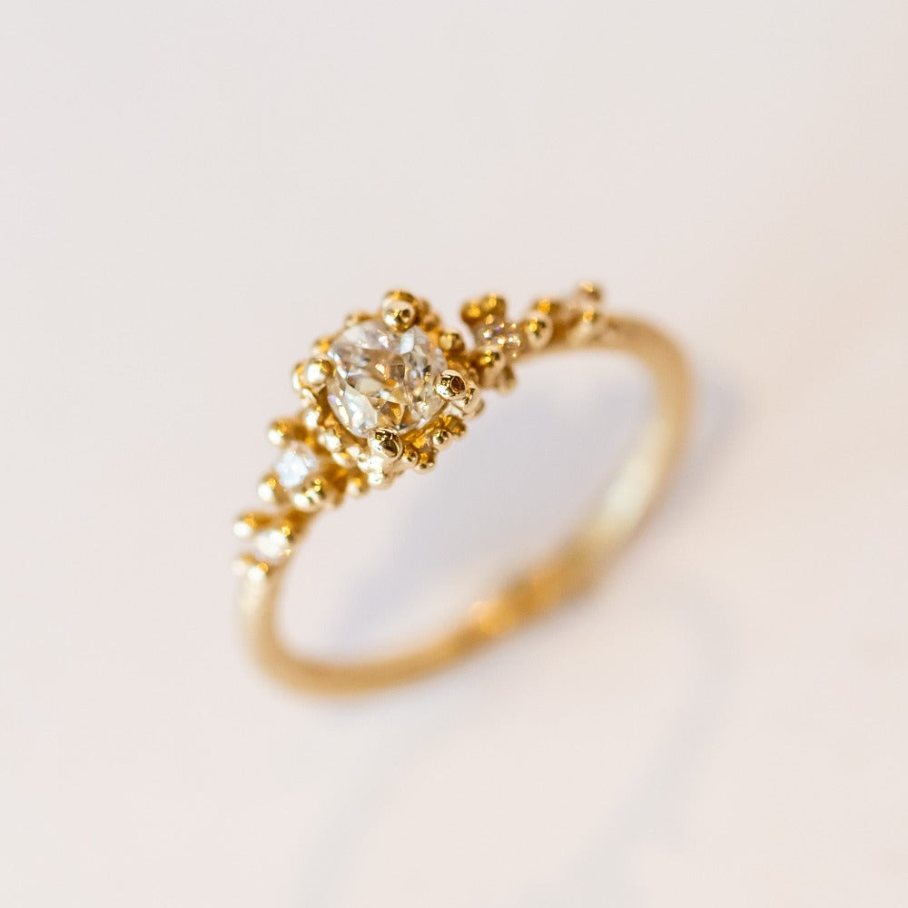 Unique antique cut diamond engagement ring with golden granules, on a gently textured band.
