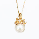 A cluster of golden granules holds a white pearl in this pendant necklace on a cable chain.
