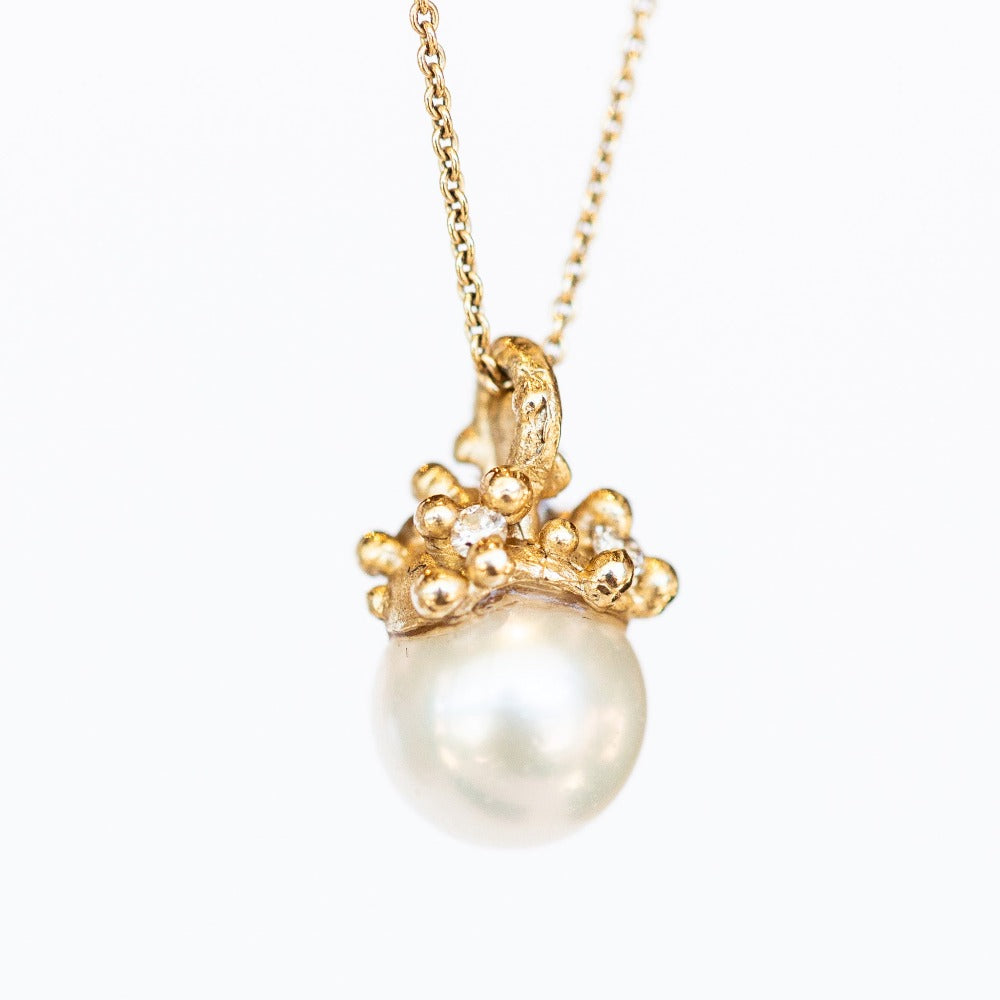A cluster of golden granules holds a white pearl in this pendant necklace on a cable chain.