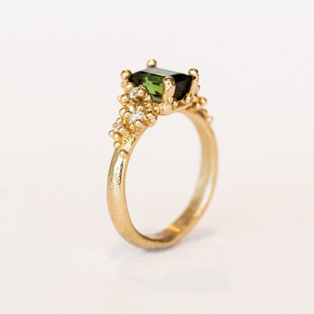 A beautiful deep green tourmaline&nbsp;ring with white&nbsp;diamonds and granules of yellow gold, on a lightly textured band.