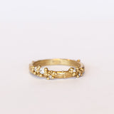 A stackable band featuring five white diamonds nestling amongst granules of yellow gold on a gently textured half round band.
