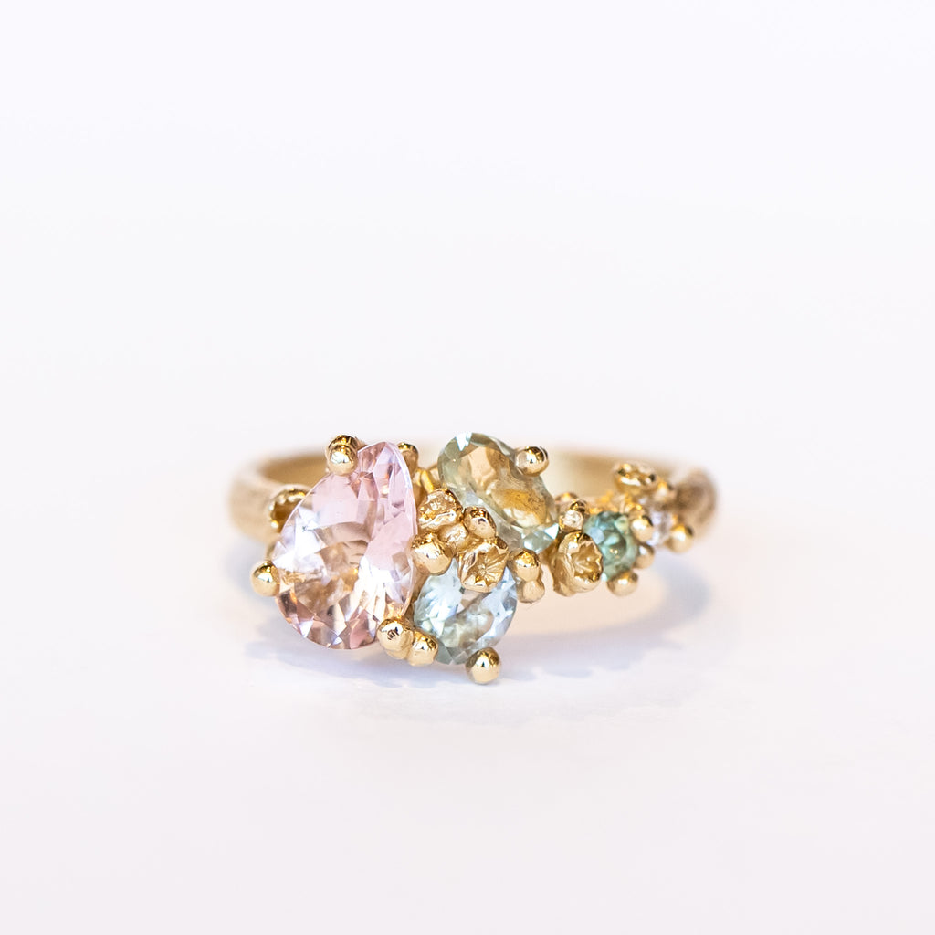 An asymmetrical gold cluster ring set with a variety of pastel gemstones amongst gold granules.