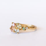 An asymmetrical gold cluster ring set with a variety of pastel gemstones amongst gold granules.