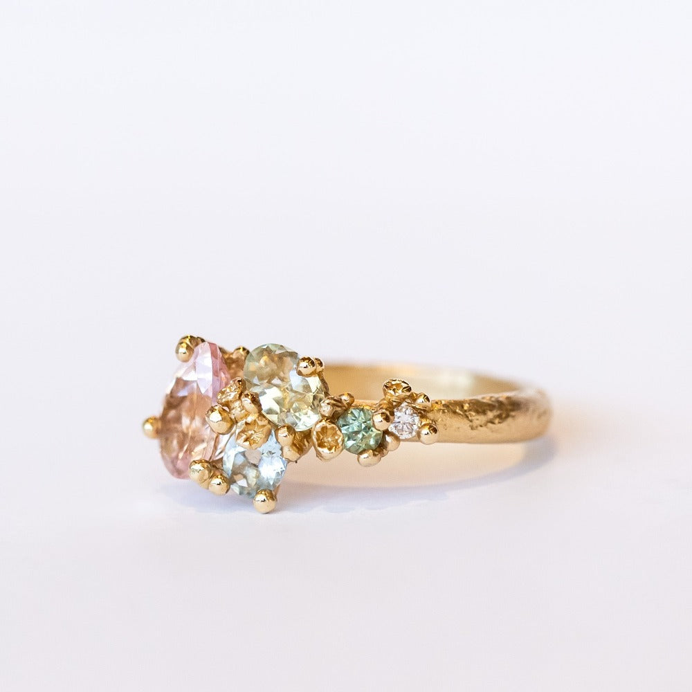 An asymmetrical gold cluster ring set with a variety of pastel gemstones amongst gold granules.