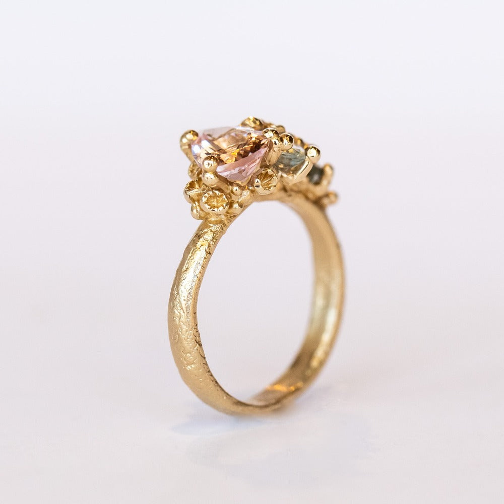 An asymmetrical gold cluster ring set with a variety of pastel gemstones amongst gold granules.
