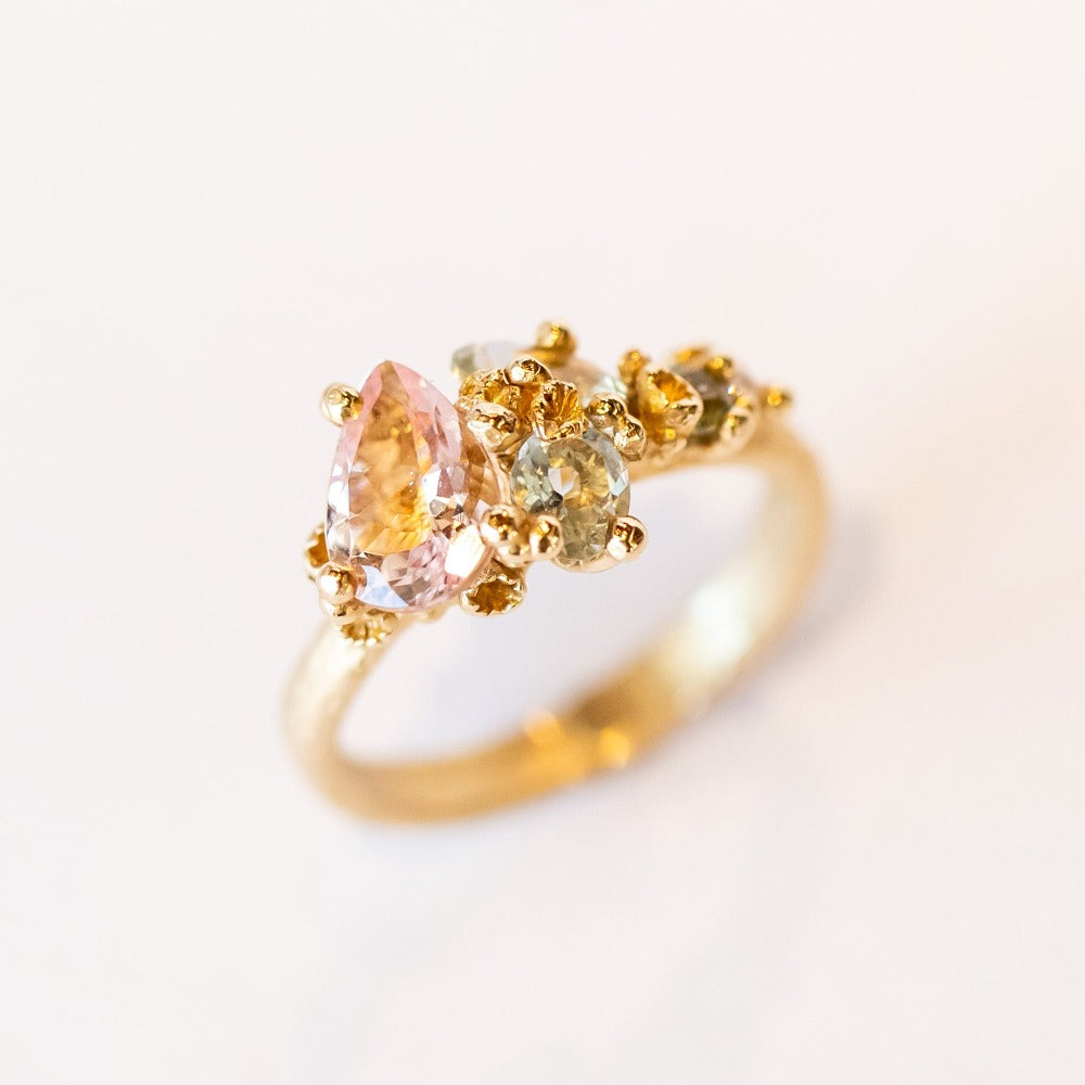 An asymmetrical gold cluster ring set with a variety of pastel gemstones amongst gold granules.
