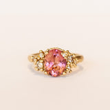 Oval peach-pink tourmaline set amongst&nbsp;golden granules and diamonds in yellow gold, on a gently textured band.
