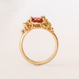 Oval peach-pink tourmaline set amongst&nbsp;golden granules and diamonds in yellow gold, on a gently textured band.