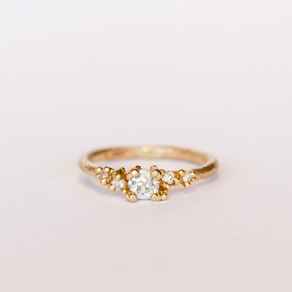 Unique antique cut diamond alternative engagement ring with golden granules, on a gently textured band.