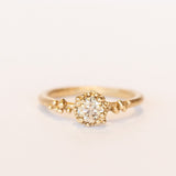 A round diamond solitaire engagement ring set in a granulated setting in yellow gold.