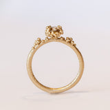 A round diamond solitaire engagement ring set in a granulated setting in yellow gold.