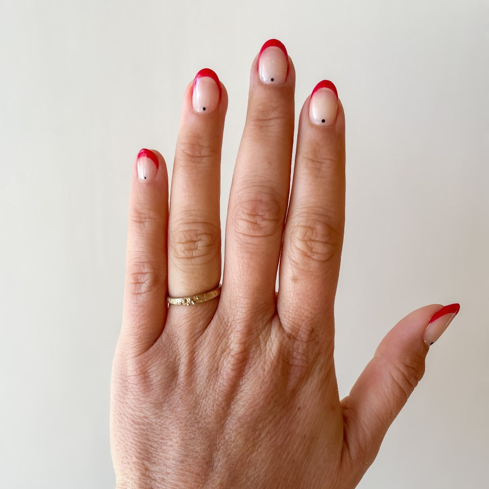 A textured yellow gold band with one tiny diamond set in gold granules.