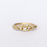 Unique diamond cluster engagement ring with golden granules, on a gently textured band.