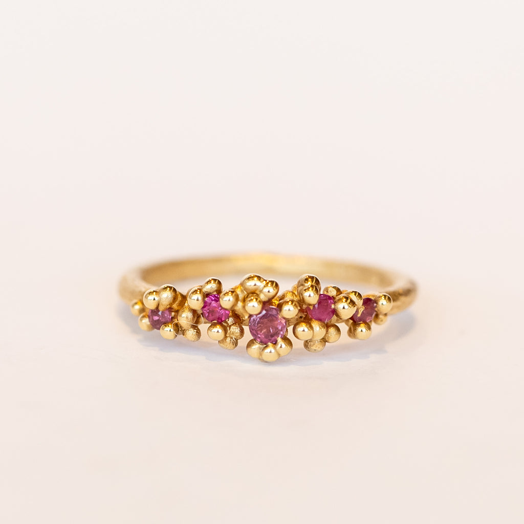 Unique ruby cluster ring with golden granules, on a gently textured band.