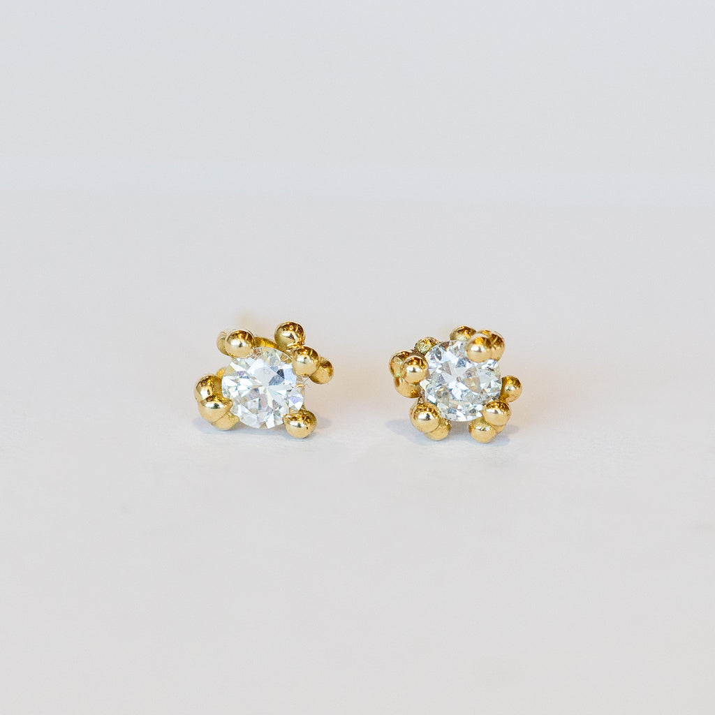 Unique solitaire diamond stud earrings with golden granules in yellow gold.