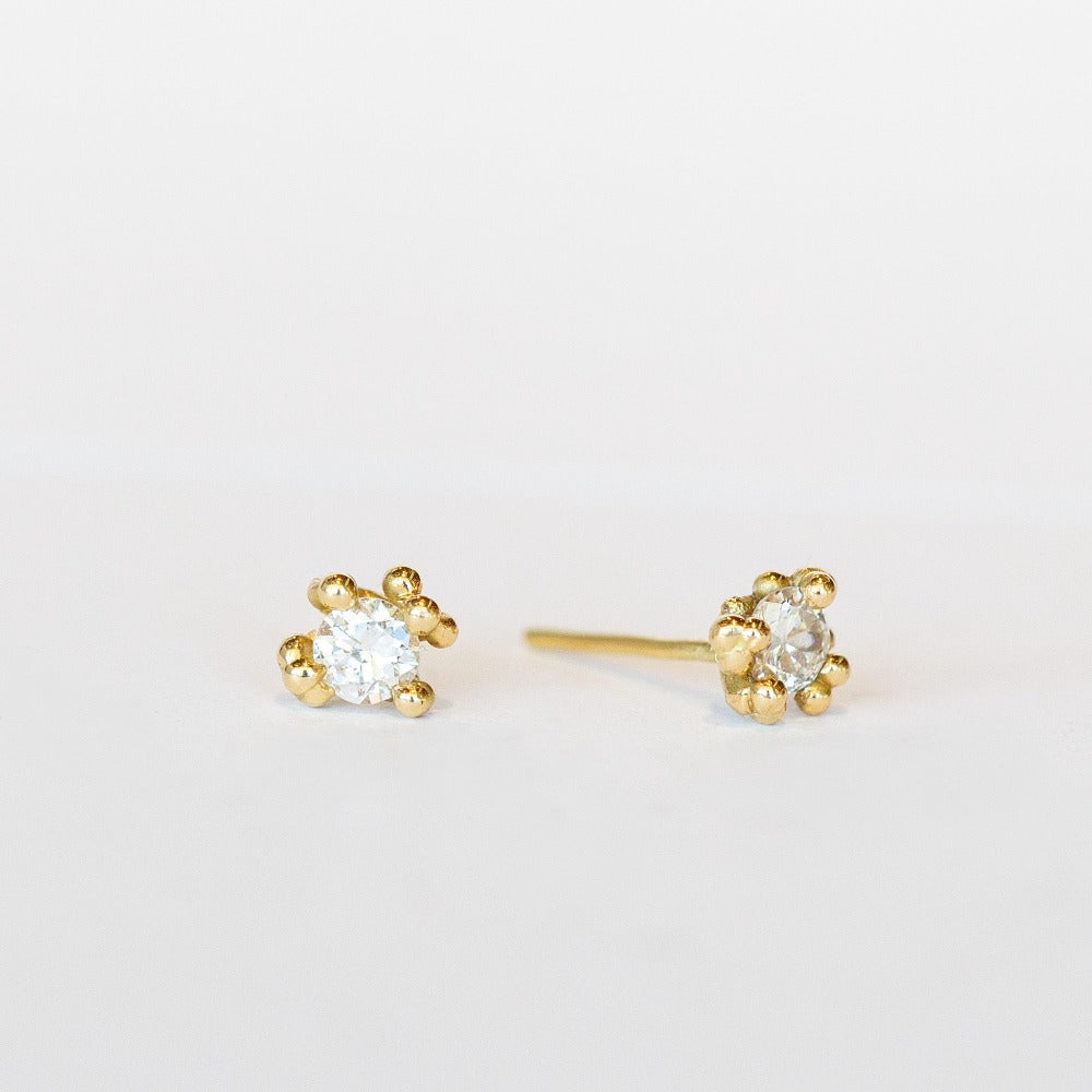 Unique solitaire diamond stud earrings with golden granules in yellow gold.