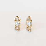 A pair of gold stud earrings set with white, grey, and champagne diamonds.