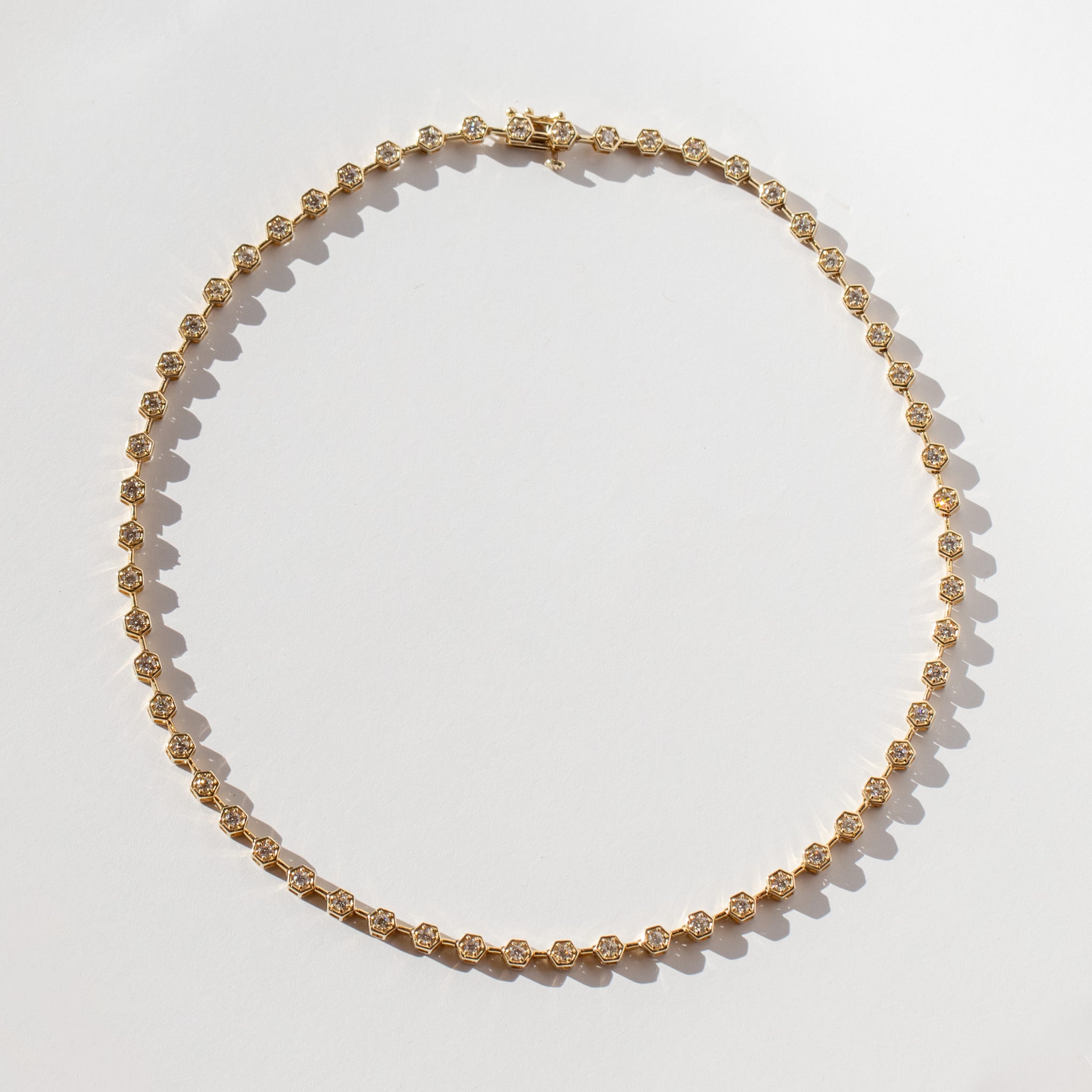 A diamond tennis necklace made up of hexagonal links each set with a small round diamond.