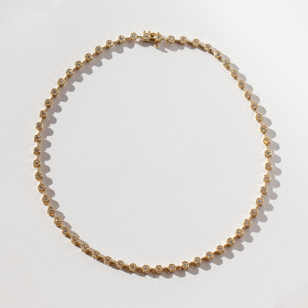 A diamond tennis necklace made up of hexagonal links each set with a small round diamond.