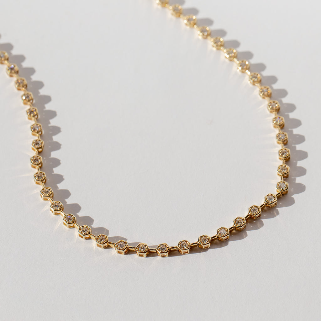 A diamond tennis necklace made up of hexagonal links each set with a small round diamond.