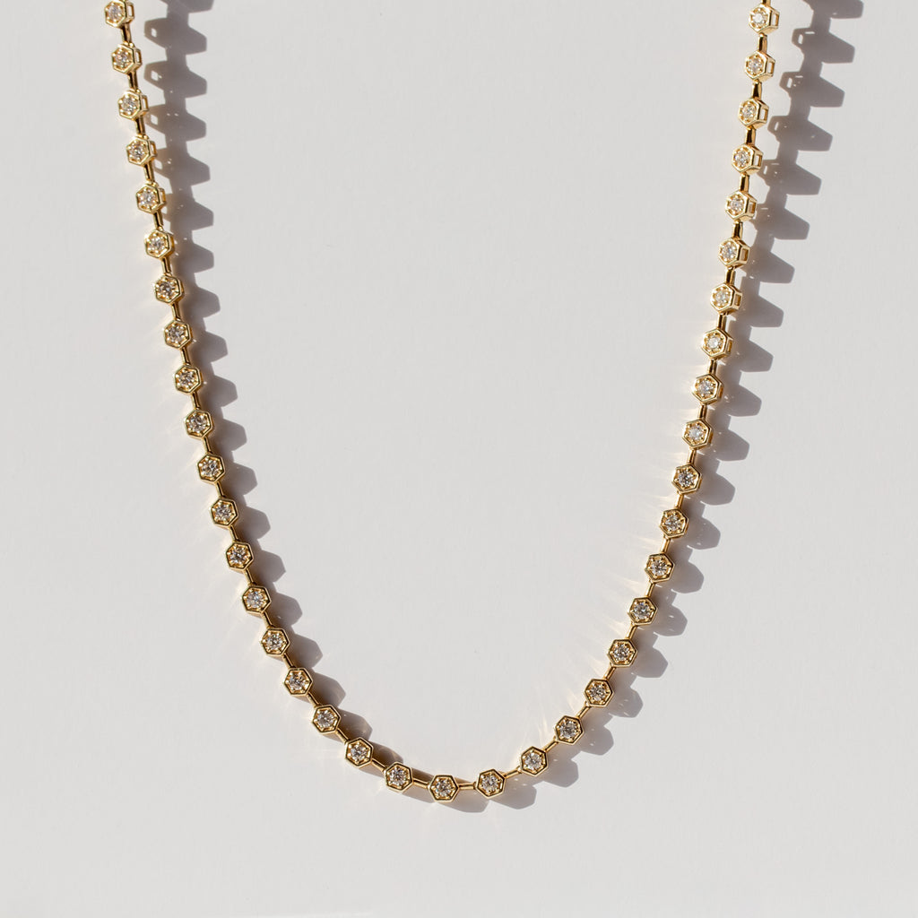 A diamond tennis necklace made up of hexagonal links each set with a small round diamond.
